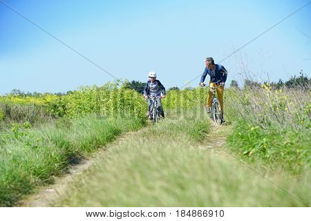 Father with kids riding bicycle in countyside