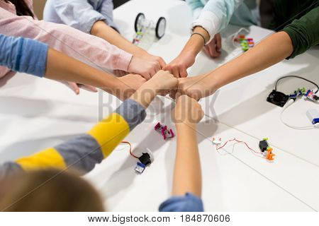 education, children, technology, science and people concept - group of happy kids with building kit making fist bump at robotics school