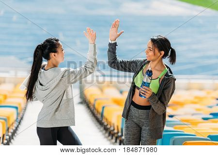 Two Young Sportswomen With Sport Bottle Giving Highfive On Stadium Stairs