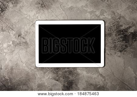 Tablet computer on grey stone background. Top view. Flat lay style.