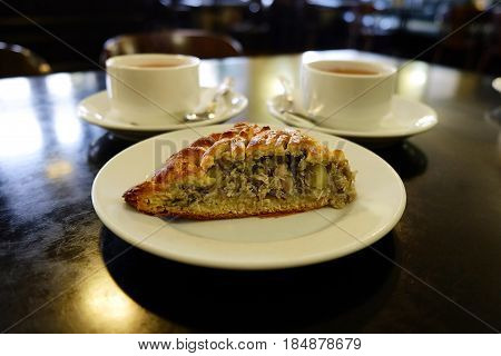 a piece of cake on a saucer and two cups of tea in a cozy cafe