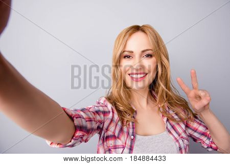 Young Beautiful Woman In Checkered Shirt Taking Self Portrait And Showing V-sign
