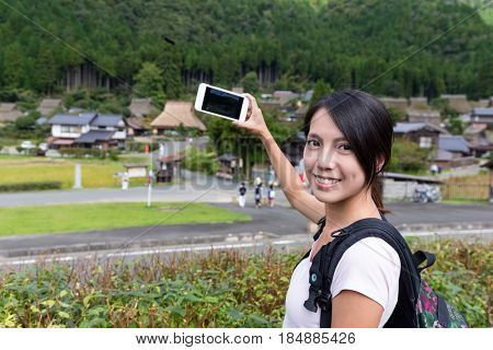 Travel Woman taking photot on cellphone in miyama of Kyoto