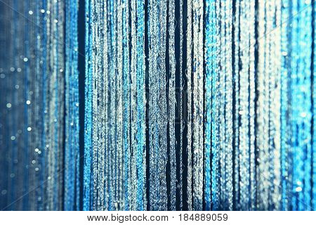 Background texture curtains made of blue threads with glitter and blur at the edges. Fibers of threads of blue curtains sparkle in the light.