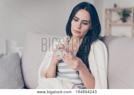 Portrait Of Troubled Ill Young Woman Sitting At Home Holding Glass Of Water And Reading Discription