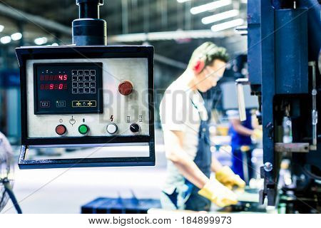 Asian machine operator in production plant checking data 