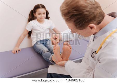 Try to move it. Regular competent local rheumatologist conducting a general checkup and running a test while his patient sitting on the bed