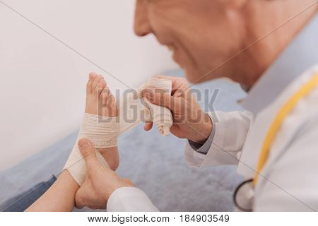 Isnt it too tight. Gentle accurate experienced rheumatologist using medical bondage for fixing childs joints and allowing her moving freely