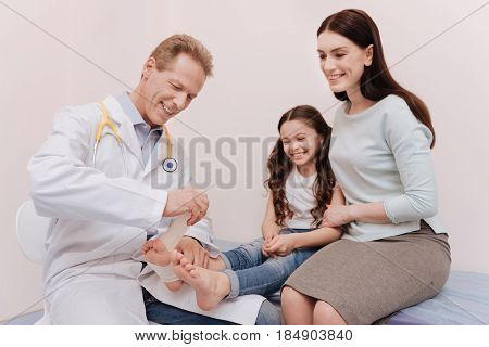 Careful expert. Nice positive local rheumatologist treating little patient who sitting in his office with her mom