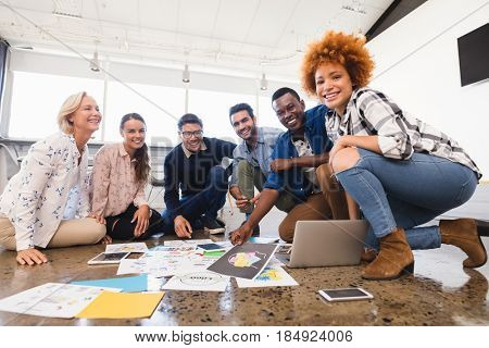 Portrait of smling creative business team working together on floor at office