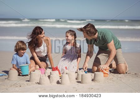 Cheerful family making sand castle at beach during sunny day