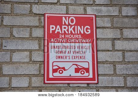 no parking towing sign on brick background in urban area