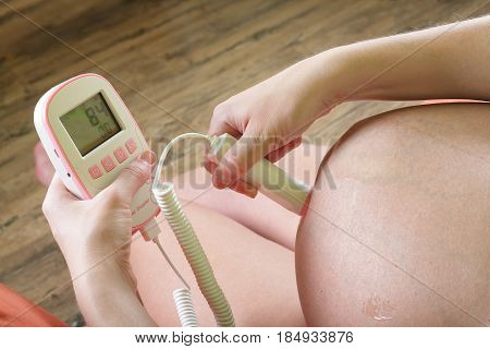 Pregnant woman with the help by a fetal doppler controls a condition of a fetus.