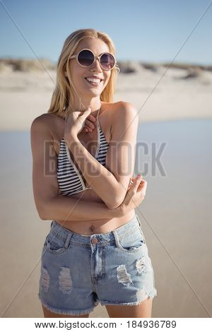 Happy young woman wearing sunglasss at beach during sunny day