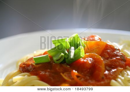 Deska špagety s rajčatovou omáčkou s párou coming out. Zaměřte se na zelené obloha.