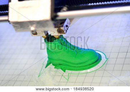 3D printer prints the form of molten plastic green close-up. Automatic three dimensional 3d printer performs plastic modeling in laboratory. Progressive modern additive technology