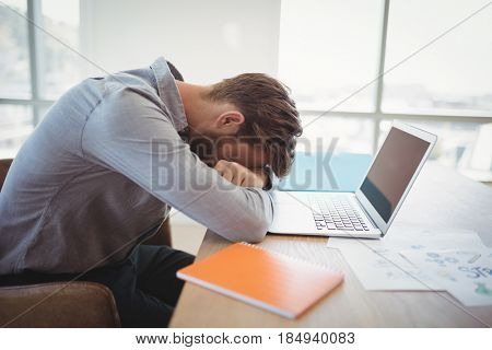 Tired executive leaning on desk in office