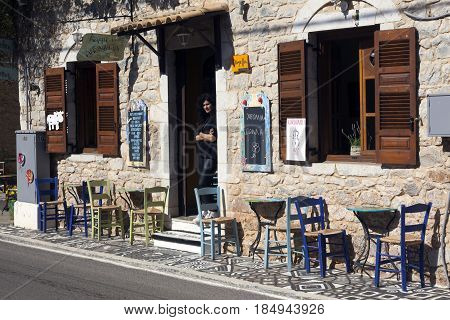kardamili, Greece, 25 april 2017: waitress waits for customers in open door of old tavern in Mani village of cardamili on peloponnese in greece on sunny spring day