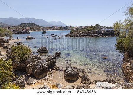 beautiful beach of Stoupa in greece on sunny day in spring on peloponnese with lonely figure and fresh green spring vegetation