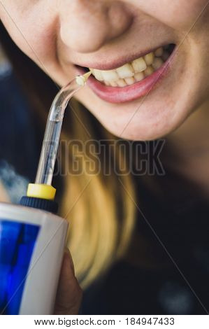 A Woman Using An Oral Irrigator In Bathroom