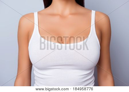 Close Up Of Perfect Lady`s Chest With Bronze Skin In White Singlet On Light Blue Background