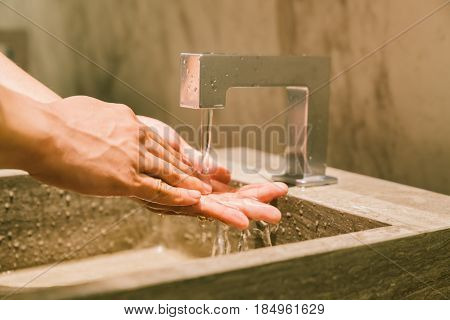 Man washing hands in public restroom. Modern WC sanitary or hygienic healthy lifestyle concept