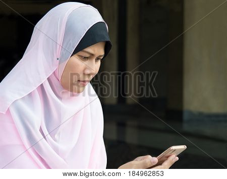 happy muslim woman with full hijab in pink dress asian traditonal style dress using smart phone