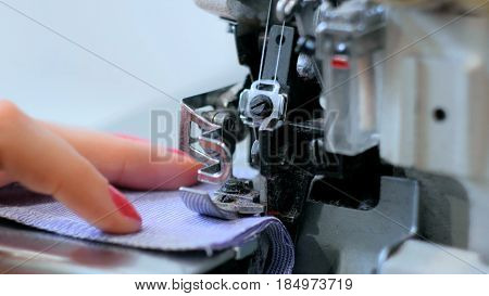 Professional tailor, seamstress using overlocking sewing machine. Fashion and tailoring concept