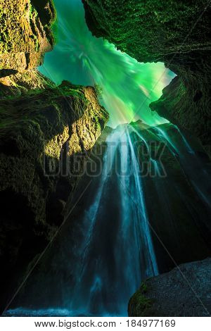 Green aurora light behind unique Gljufrabui waterfall in cave. Iceland, Europe. Courtesy of NASA. Photo collage