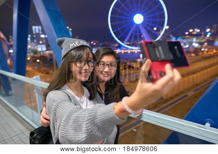 HONG KONG - CIRCA DECEMBER, 2015: women taking a selfie in Hong Kong. A selfie is a self-portrait photograph, typically taken with a camera phone held in the hand or supported by a selfie stick.
