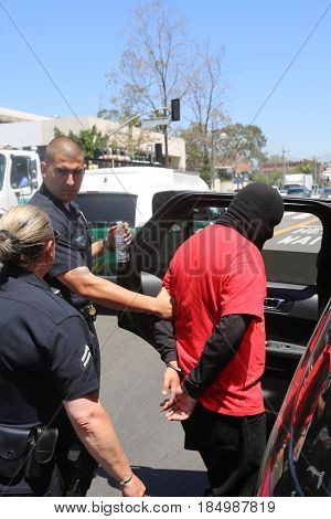 LOS ANGELES California- May 1, 2017: A person in a Black Ski Mask is arrested and put in a police car at a Protest Rally Against President Donald J.Trump on May 1, 2017 in Los Angeles, California
