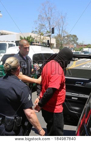 LOS ANGELES California- May 1, 2017: A person in a Black Ski Mask is arrested and put in a police car at a Protest Rally Against President Donald J.Trump on May 1, 2017 in Los Angeles, California
