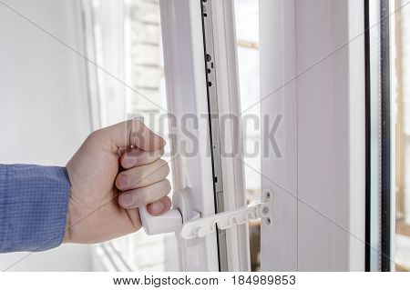 The hand holds the handle of opened window with safe restrictor lock prevents accidental shut