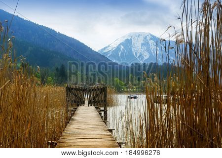 Wooden jetty with gate in the tegernsee lake snow-covered mountains in the background landscape in the famous tourist resort in the bavarian alps bavaria germany europe
