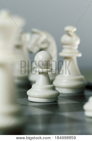 Chess figure pawn on board. Chess game play closeup. Chess figures with focus on pawn. Bishop Knight and Queen on background. Vertical image of checkmate. Intellectual board game. Strategic advantage