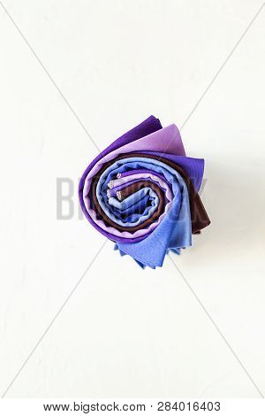 Colorful Fabric Swatches Rolled Up On White Background.