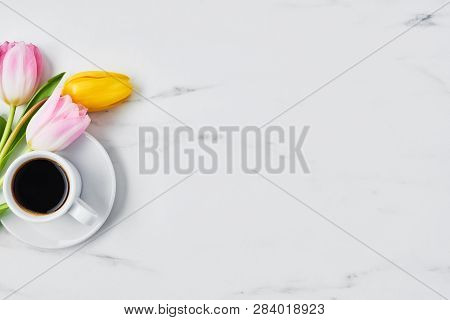 Cup Of Coffee With Tulips On White Marble Table. Spring Flowers. Top View. Copy Space For Text. Spri