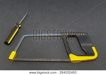 A Set Of Tools On A Gray Background Pliers, Screwdriver, Saw.