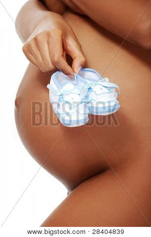 mujer de prägnant desnuda, sostiene pequeños zapatos azules delante de su vientre, de pie sobre un blanco backgrou