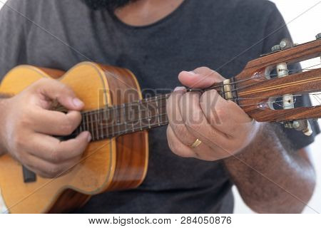 Young Man Playing Ukulele With Shirt And Black Pants.