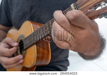 Young Man Playing Ukulele With Shirt And Black Pants.