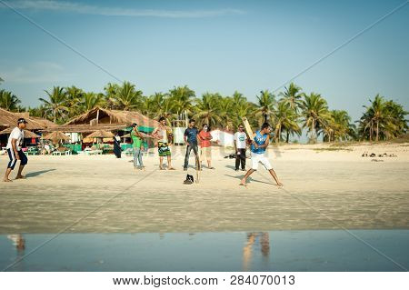 India, Goa - November 15, 2012: Friends play cricket on the beach of GOA in India. The guys play Indian baseball on the beach. Indian national sport. The game of cricket at sunset