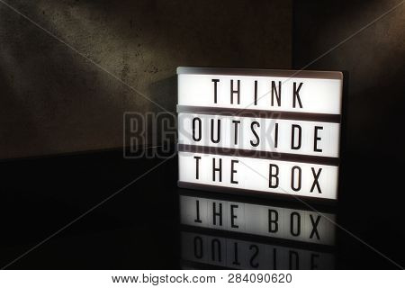 Think Outside The Box Motivational Message On A Light Box In A Cinematic Moody Background