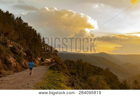 A Jogger On A Nature Trail, In The Mountains Near Jerusalem, Israel, In The Golden Hour Before Sunse