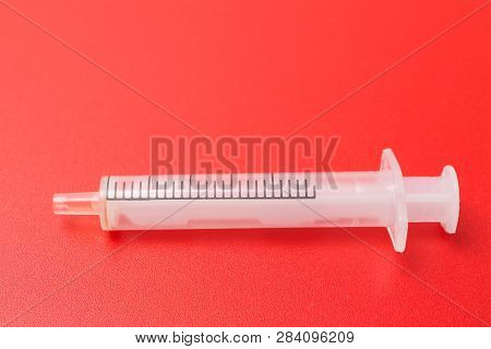 Disposable Syringe On Red Background, Pharmaceutical. Studio Shot