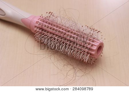 Close Up Top View Hair Fall At White Pink Plastick Comb At Wooden Table