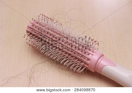 Close Up Top View Hair Fall At White Pink Plastick Comb At Wooden Table
