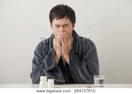 Young Sick And Ill Man In Sofa Holding Tissue Cleaning Snotty Nose Having Temperature Feeling Bad In