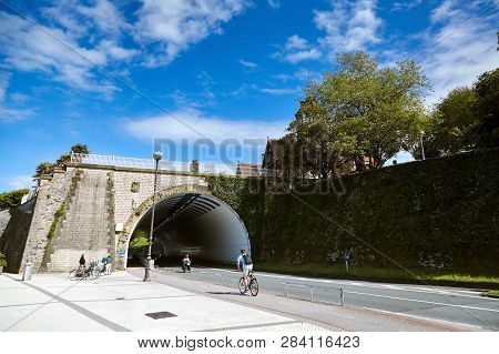 San Sebastian (donostia), Basque Country, Spain: A Young Man On A Bicycle Rides Under An Old Stone B