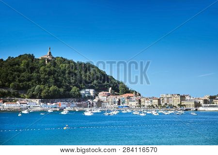 Sea Harbor In San Sebastian Or Donostia, Basque Country, Spain. View Of Jesus Christ Statue On Top O